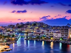small-Agios Nikolaos. Agios Nikolaos is a picturesque town in the eastern part of the island Crete built on the northwest side of the peaceful bay of Mirabello.